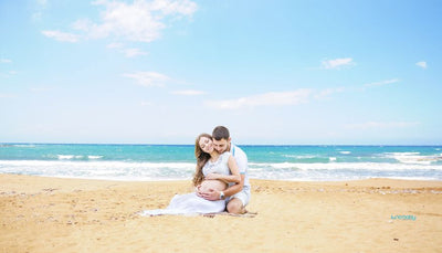 pregnant woman and her husband sitting on the beach in Miami